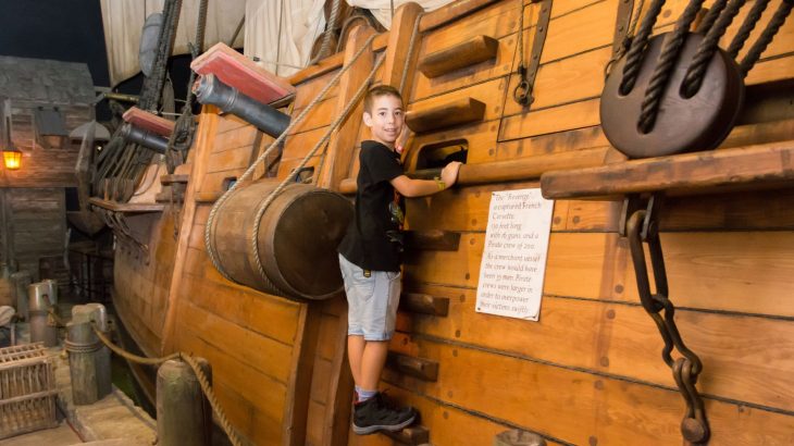 Little boy wearing black shirt playing on pirate ship at the Pirates of Nassau Museum 