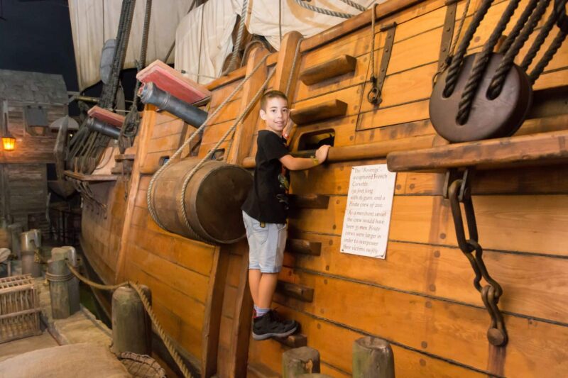 Little boy wearing black shirt playing on pirate ship at the Pirates of Nassau Museum