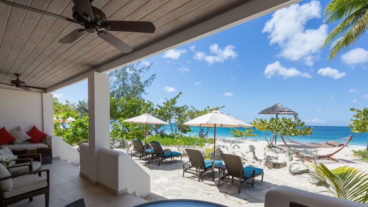 Outdoor patio overlooking beach with loungers and hammocks at Spice Island Beach Resort