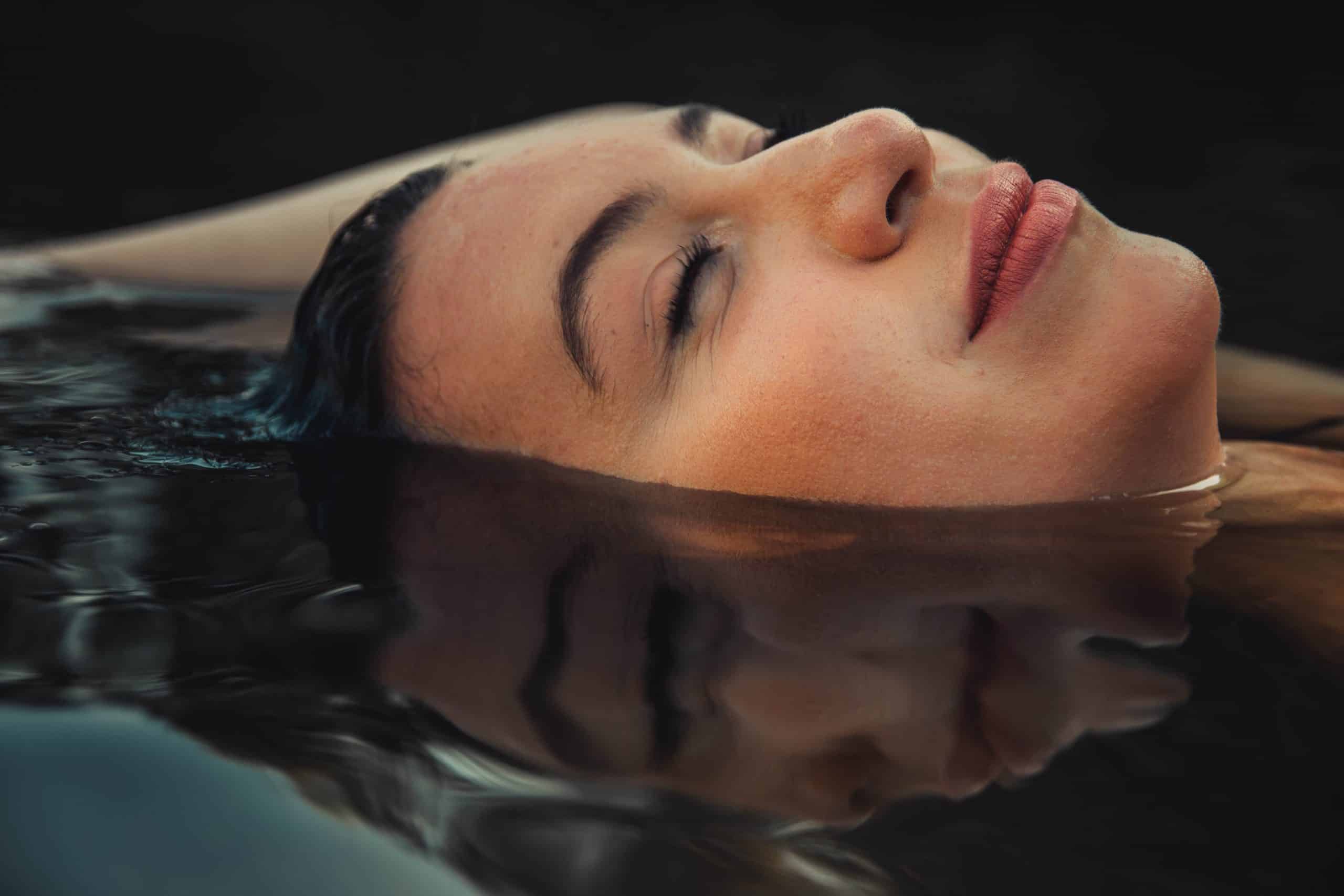A woman floating in water wearing mascara