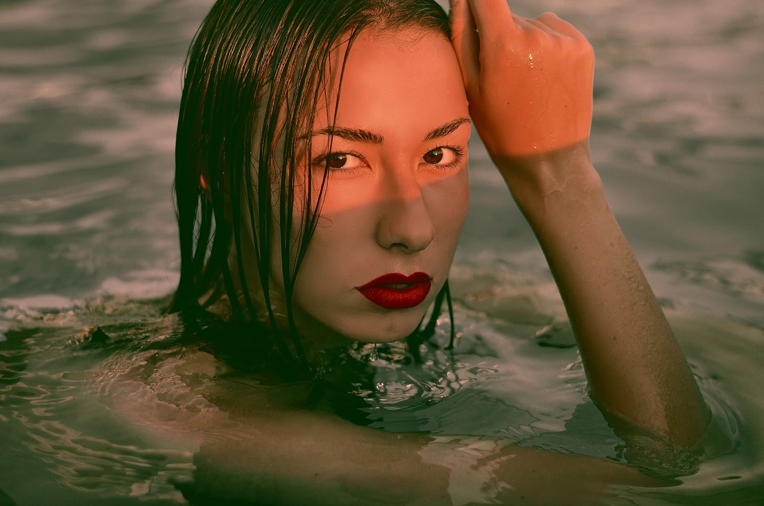 A woman swims in the ocean with red lipstick on