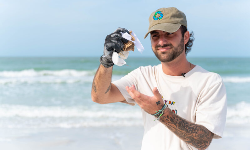 Caulin Donaldson holding up trash at beach cleanup in florida