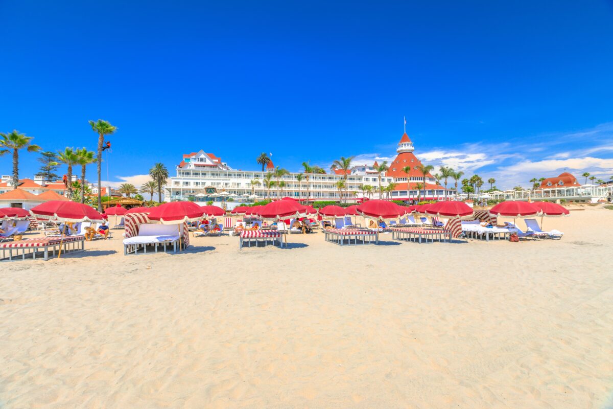 red umbrellas and beach loungers in Coronado Beach. Victorian Coronado Hotel, historic beachfront resort in Coronado Island. West coast in summer