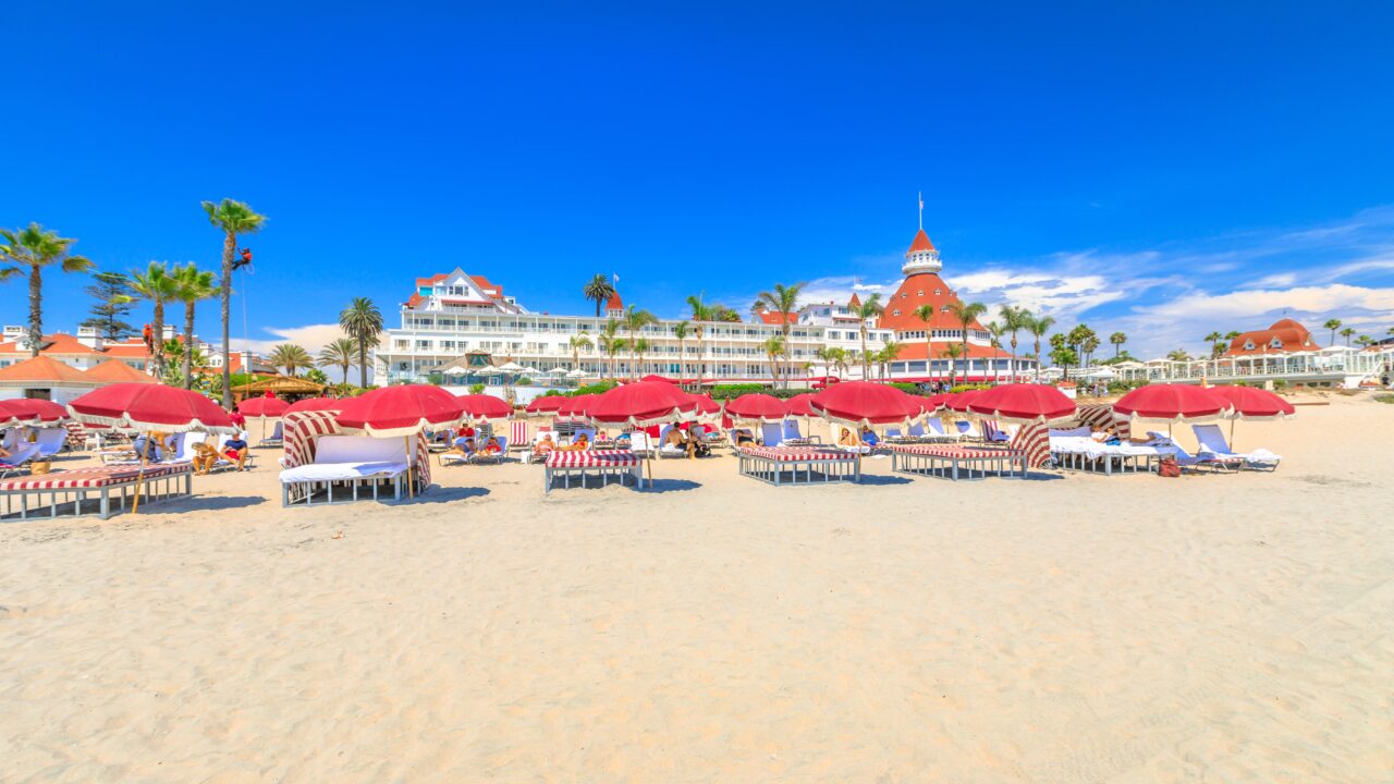 red umbrellas and beach loungers in Coronado Beach. Victorian Coronado Hotel, historic beachfront resort in Coronado Island. West coast in summer