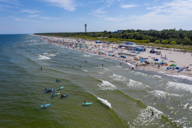 Aerial drone view of people surfing in the sea. Summer sport learning how to surf. Surfboarding in baltic sea Jastarnia, Poland, Europe