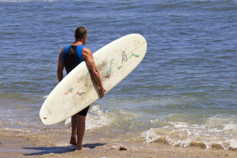 Male surfer gets ready to surf in the Pacific Ocean at San Onofre Surf Beach, California.