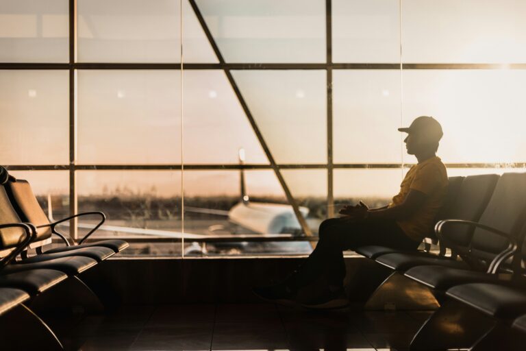 man sitting on chair in airport near window