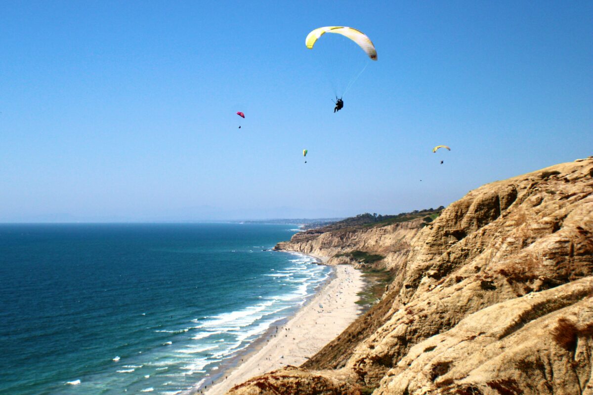 a group of people flying kites over the ocean