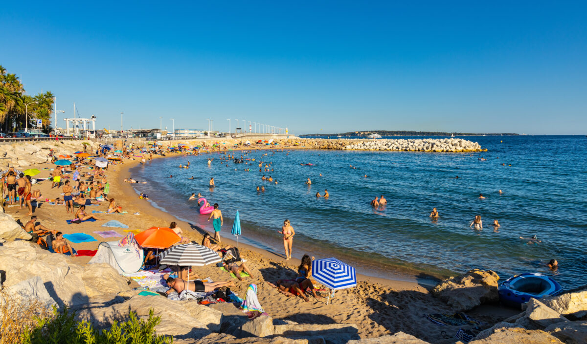 Tourists sunbathing on Plage du Midi Beach at Mediterranean Sea shore of French Riviera Azure Coast in Cannes in France.