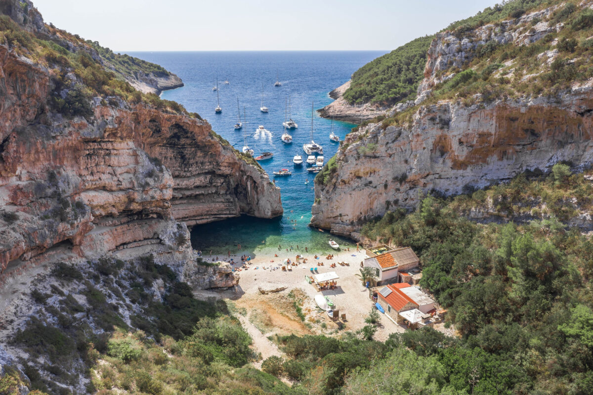 Aerial view of tourists sunbath swim at Stiniva cove beach of Adriatic sea on Vis Island in Croatia summer time.