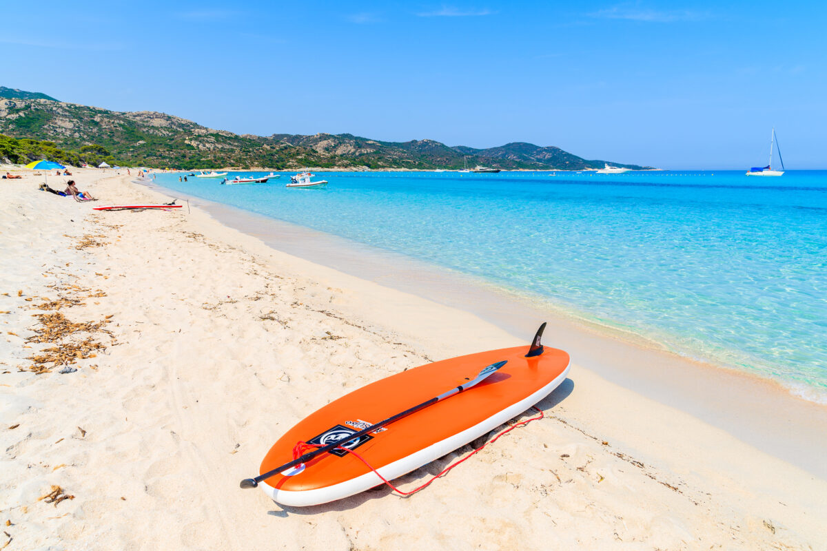 surfing board on sandy shore of idyllic Saleccia beach, Corsica island, France