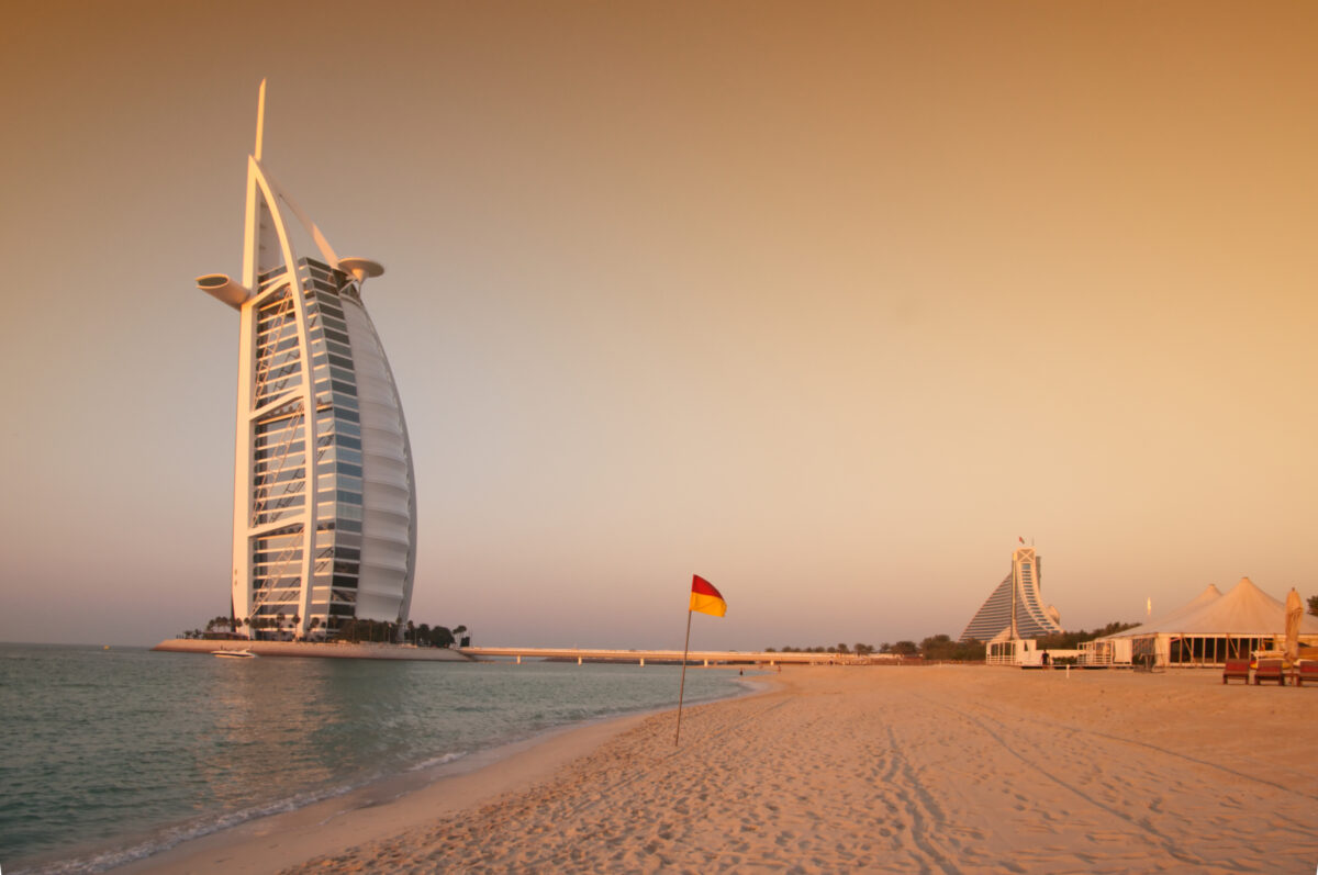 View of the luxury beach of Dubai at sunset witha gently warm light, with the Burj al arab the most exclusive hotel of the world.