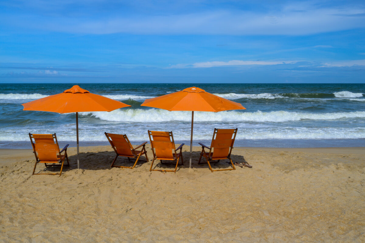 Photo of beach chairs and matching umbrellas set up on the beach of Duck, NC in the Outer Banks.