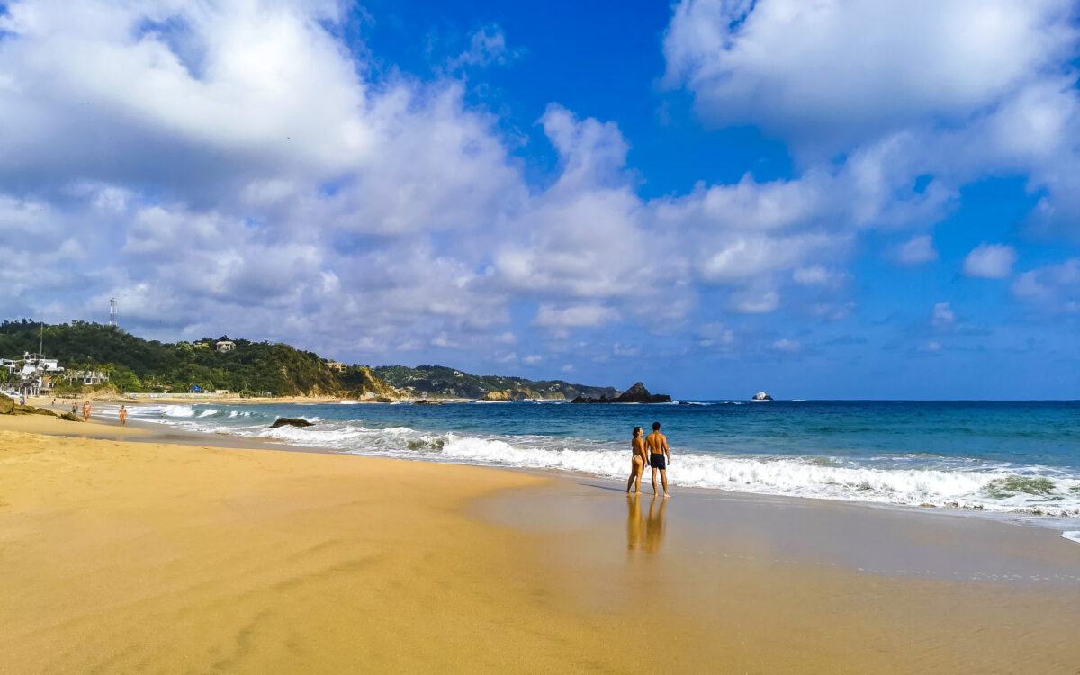 Beautiful paradise beach with mountains cliffs rocks high waves and blue sky in Mazunte Oaxaca Mexico.