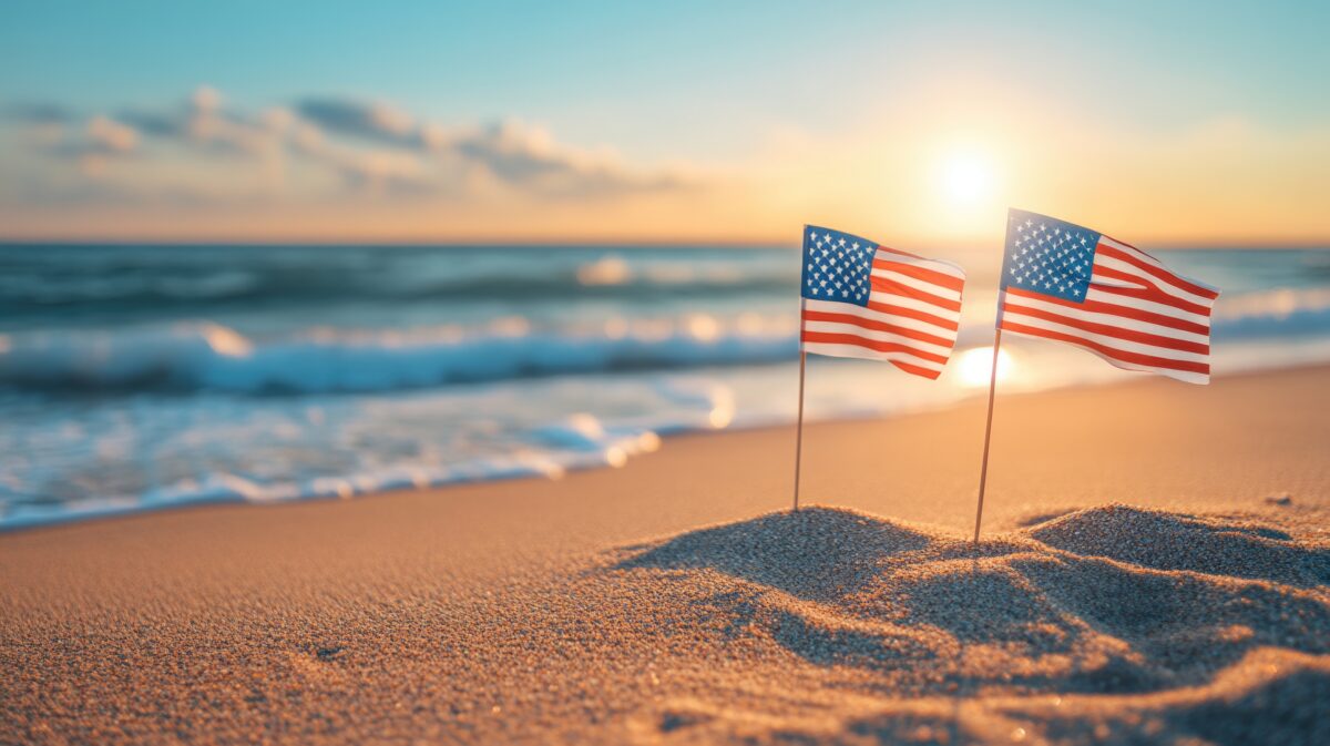 American flags on sandy beach at sunrise along ocean shoreline Happy 4th of July