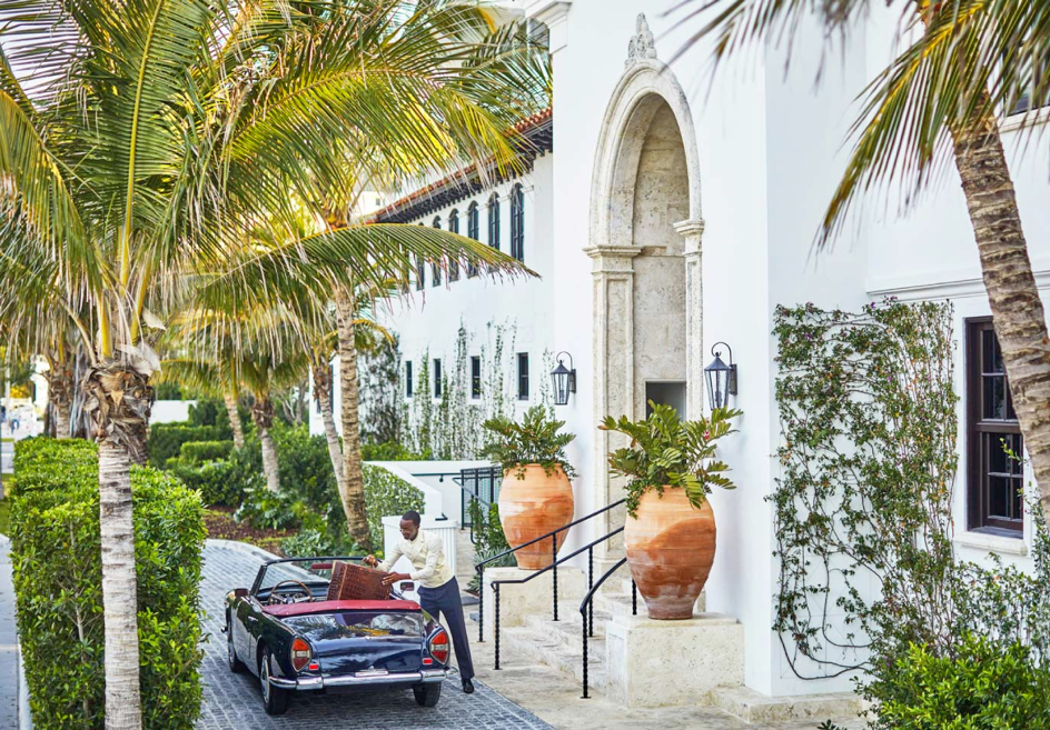 Photo of The Surf Club exterior with a bellhop assisting with a guest's luggage.