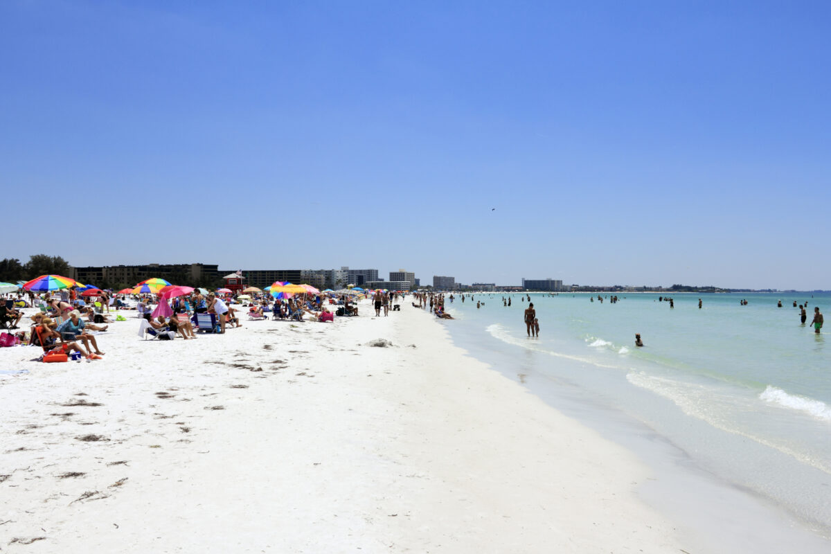 Many people relaxing on one of the top ten beaches in the United States, world renowned for its beauty and sand made of fine 99 pure white quartz that stays cool.