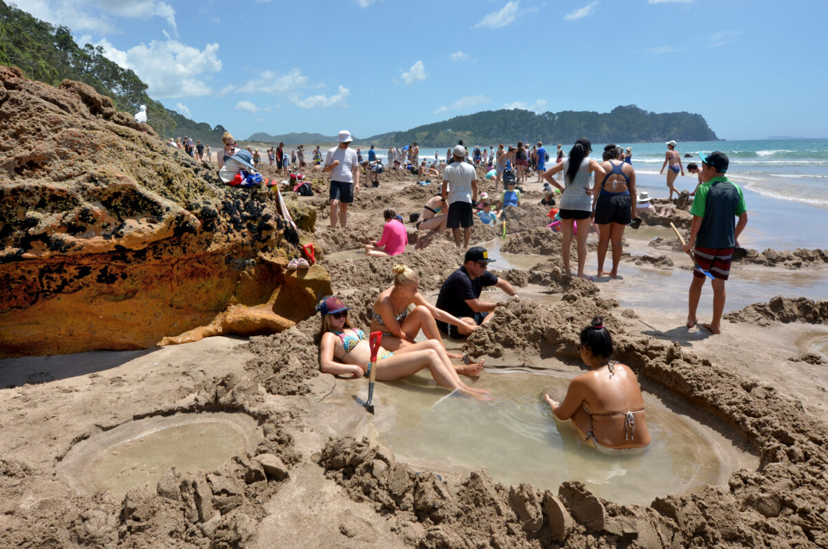 Visitors making small hot water pools in Hot Water beach. one of the most popular geothermal attractions in New Zealand.