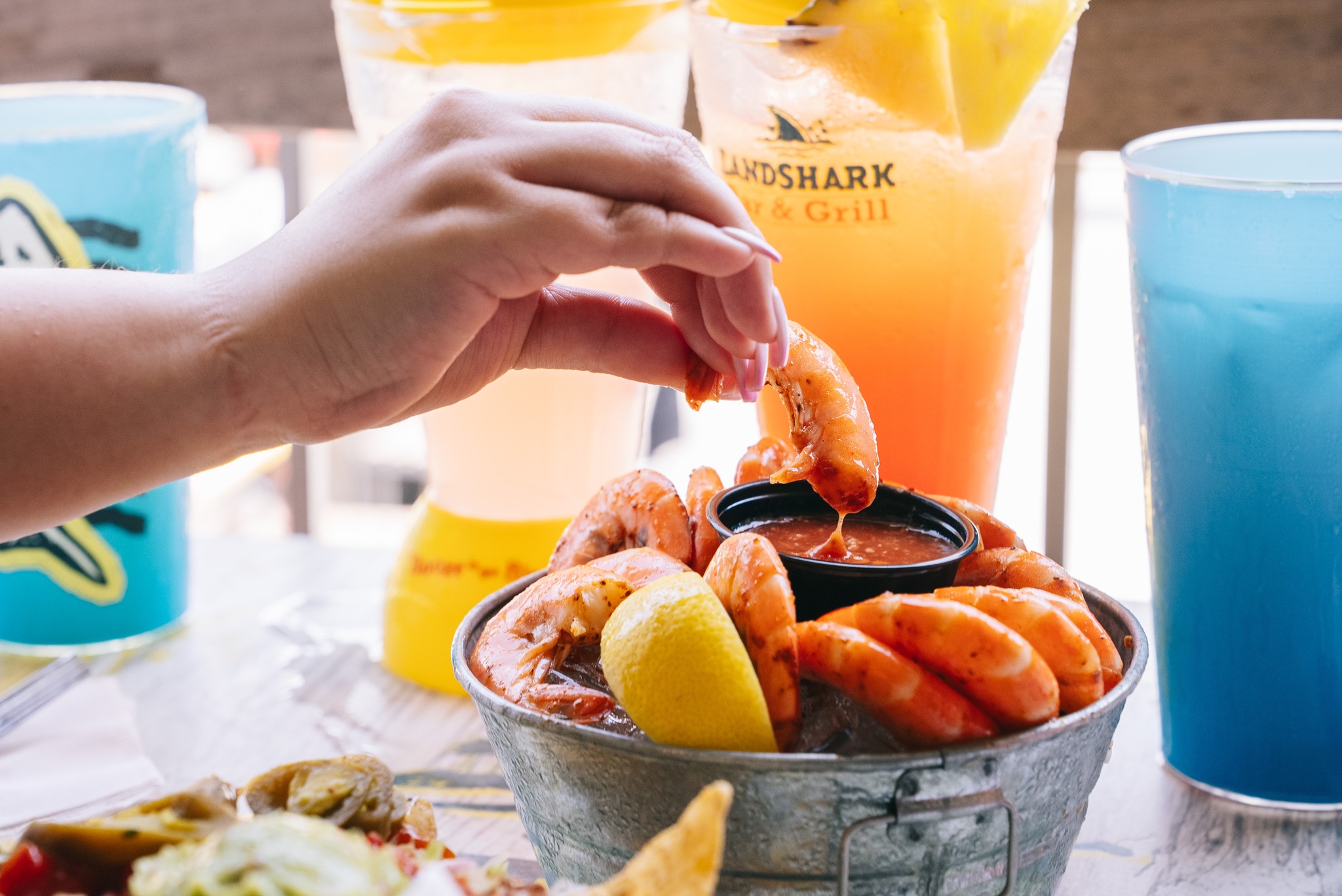 hand dipping shrimp in sauce
