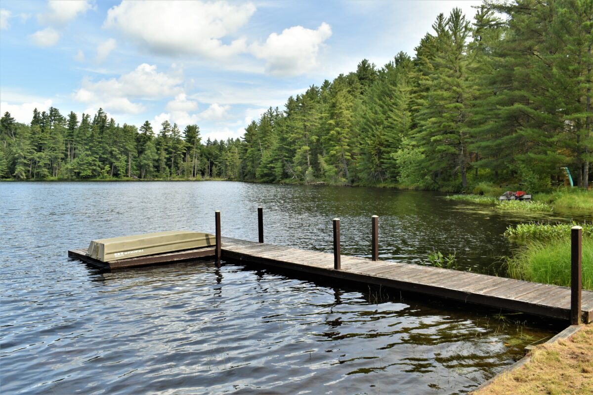 Wooden dock and boat located on Leonard Pond, located near Tupper Lake in New York.