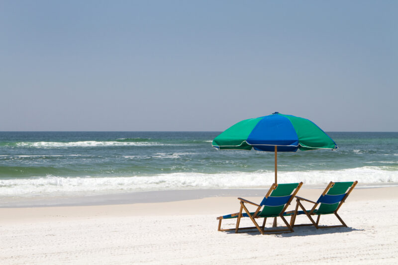 Two beach chairs and an umbrella sit on the sand at Fort Walton Beach, Florida.