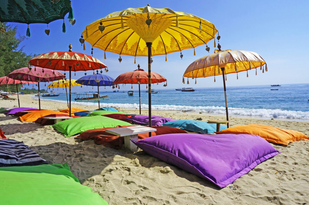Colourful beach umbrellas and sand pillows in a pristine tropical beach bathed by the Bali sea.