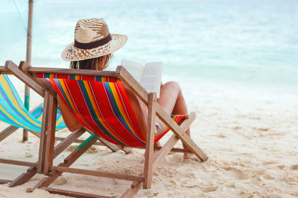 woman sitting on beach reading a book