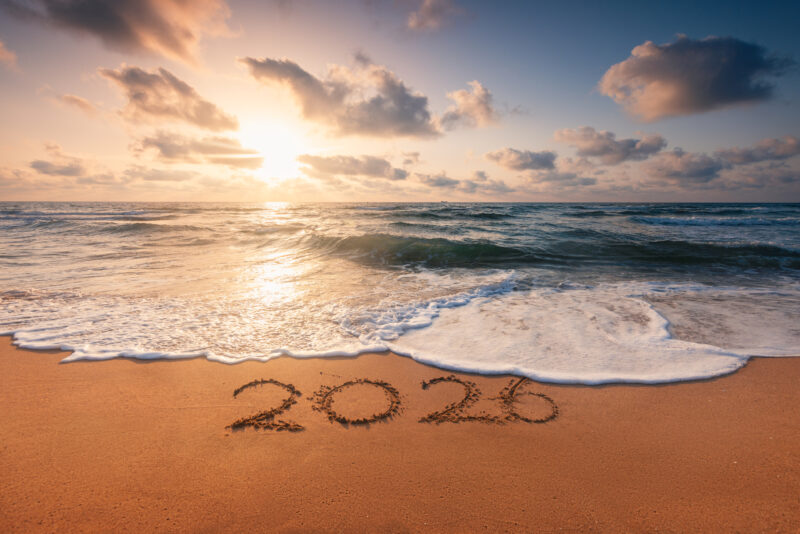 View of a sunset at a beach with "2026" written in the sand.