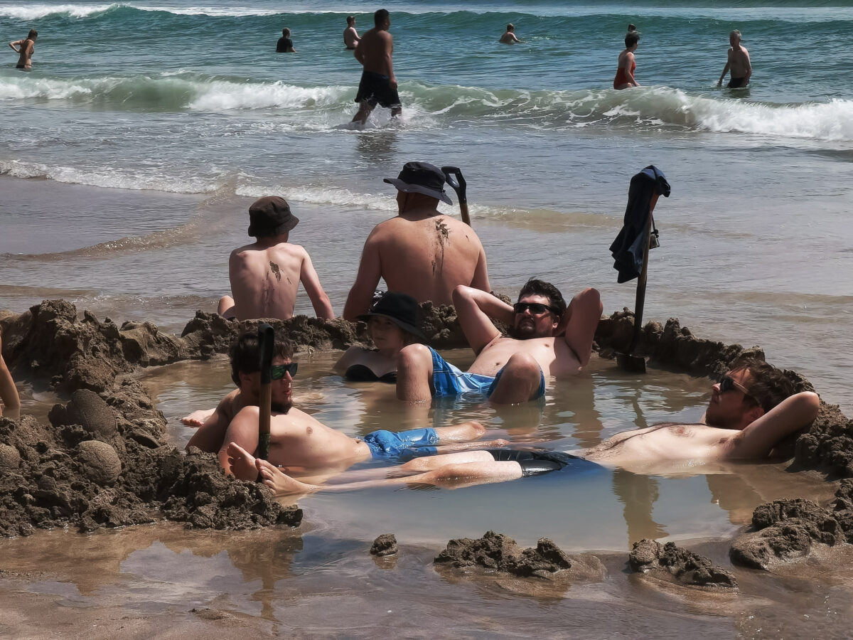close up of tourists enjoying the thermal pools at hot water beach on the north island of new zealand