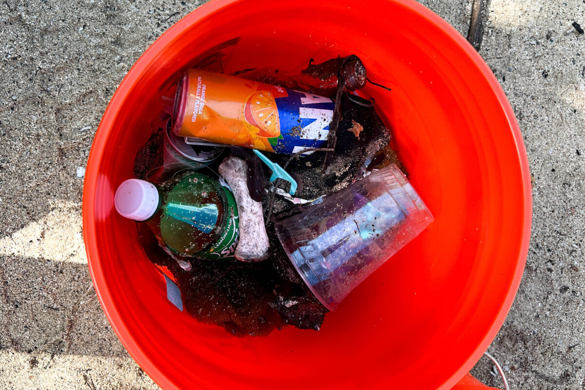 orange bucket with trash in it sitting on sand_St Croix USVI_Brandy Jo Hastings_