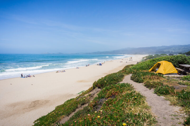 Camping on the Pacific Ocean coastal bluffs on a sunny summer day; Half Moon Bay beach in the background, California