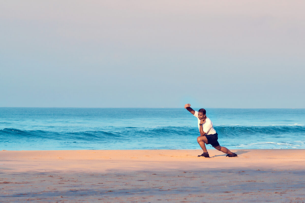 Indian man doing morning yoga asana and physical exercises on the beach. Varkala, Kerala, South India