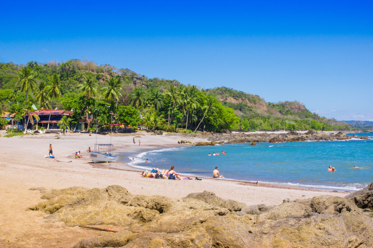 people swimming and enjoying the beautiful blue water of the beach in Playa Montezuma in Costa Rica