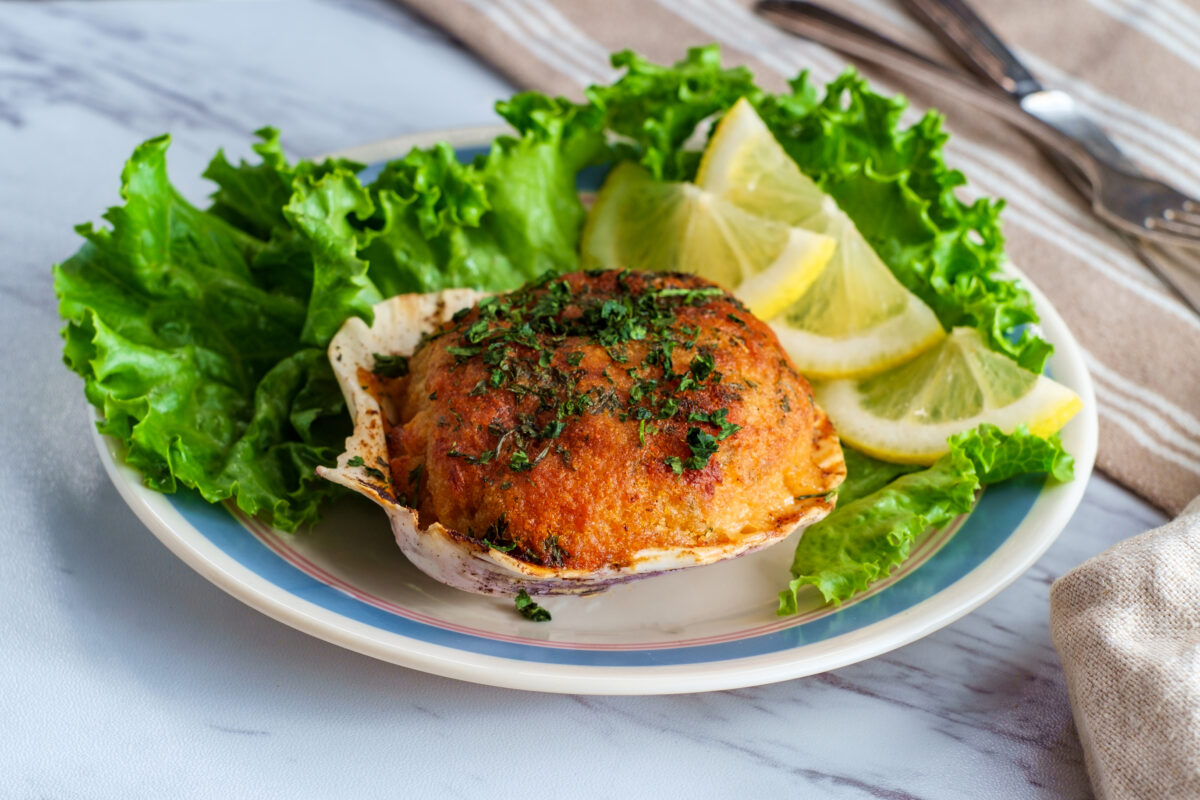 Stuffed seasoned clams garnished with romaine lettuce and lemon wedges on a marble kitchen table