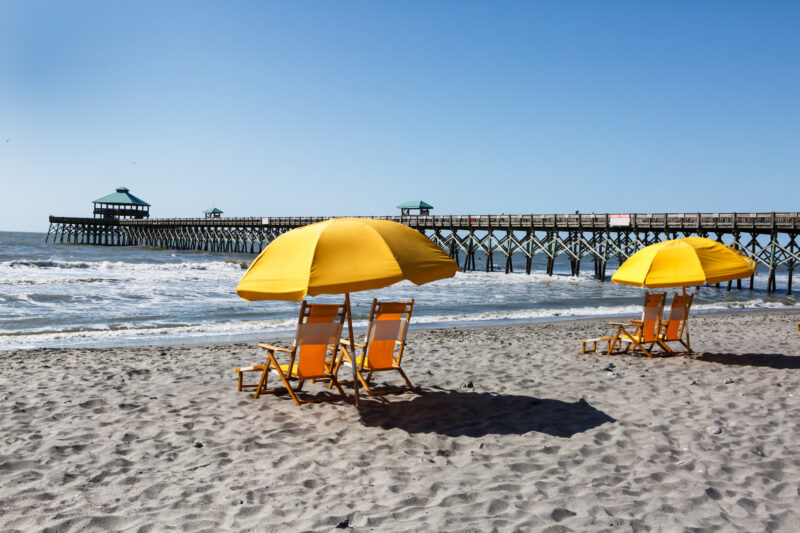 Yellow Beach Chairs under Umbrella South Carolina. Yellow beach chairs under a sun umbrella on the shore of Folly Beach near the pier in Charleston, South Carolina