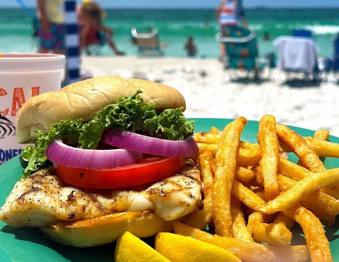 grouper sandwich with beach backdrop at Schooners