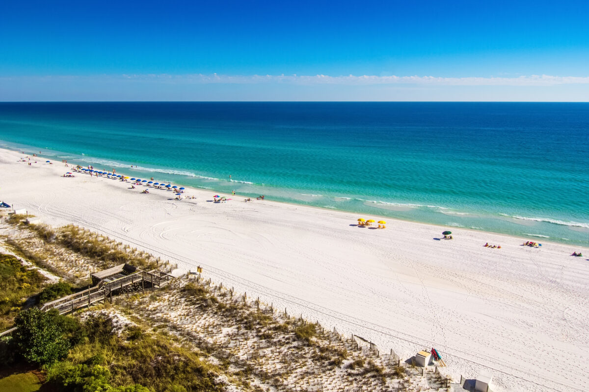 Beach goers enjoy the white sandy beaches and emerald blue waters of the panhandle in Destin, Florida
