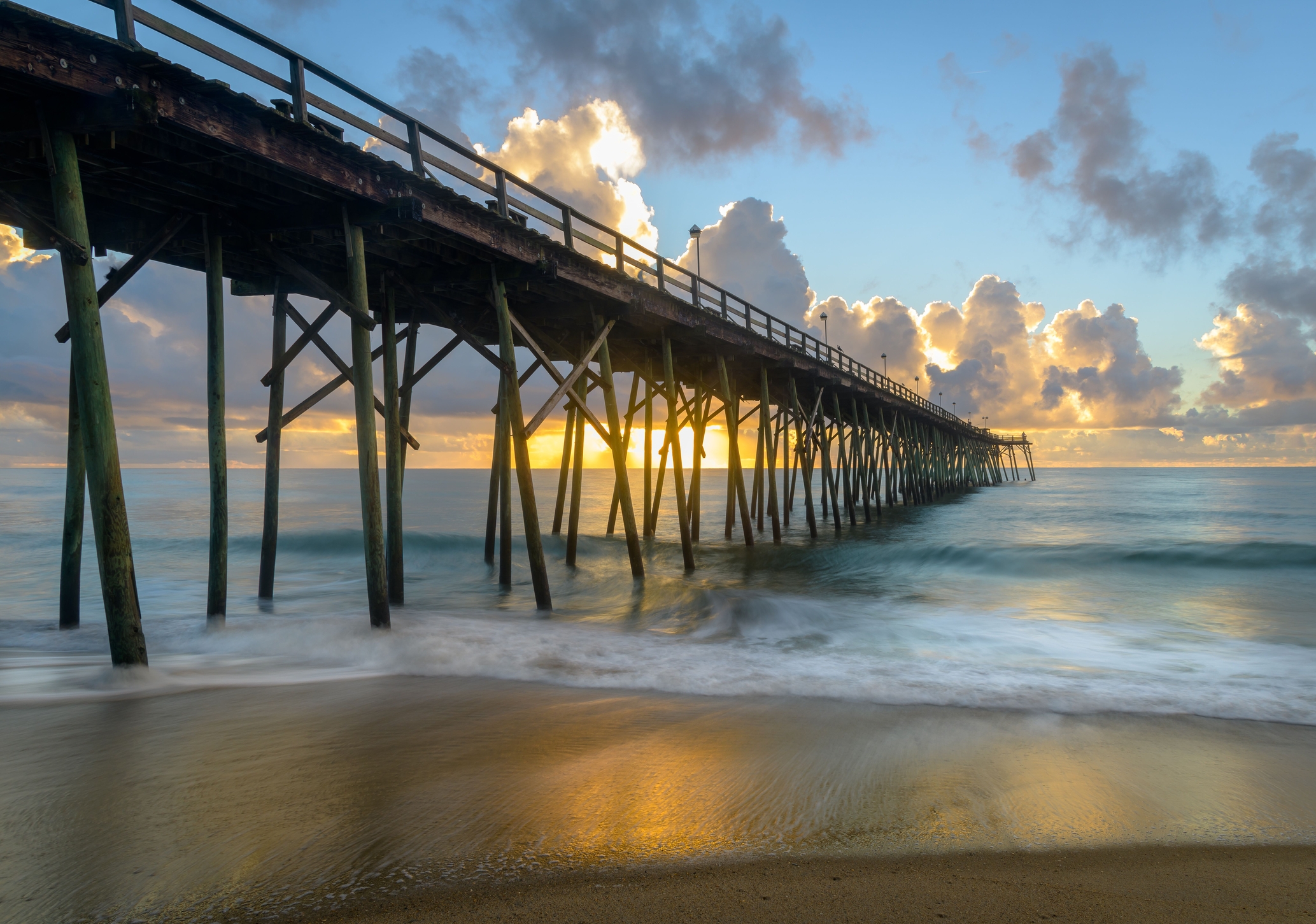 A scenic view of Carolina Beach pier during colorful sunrise, long exposure.