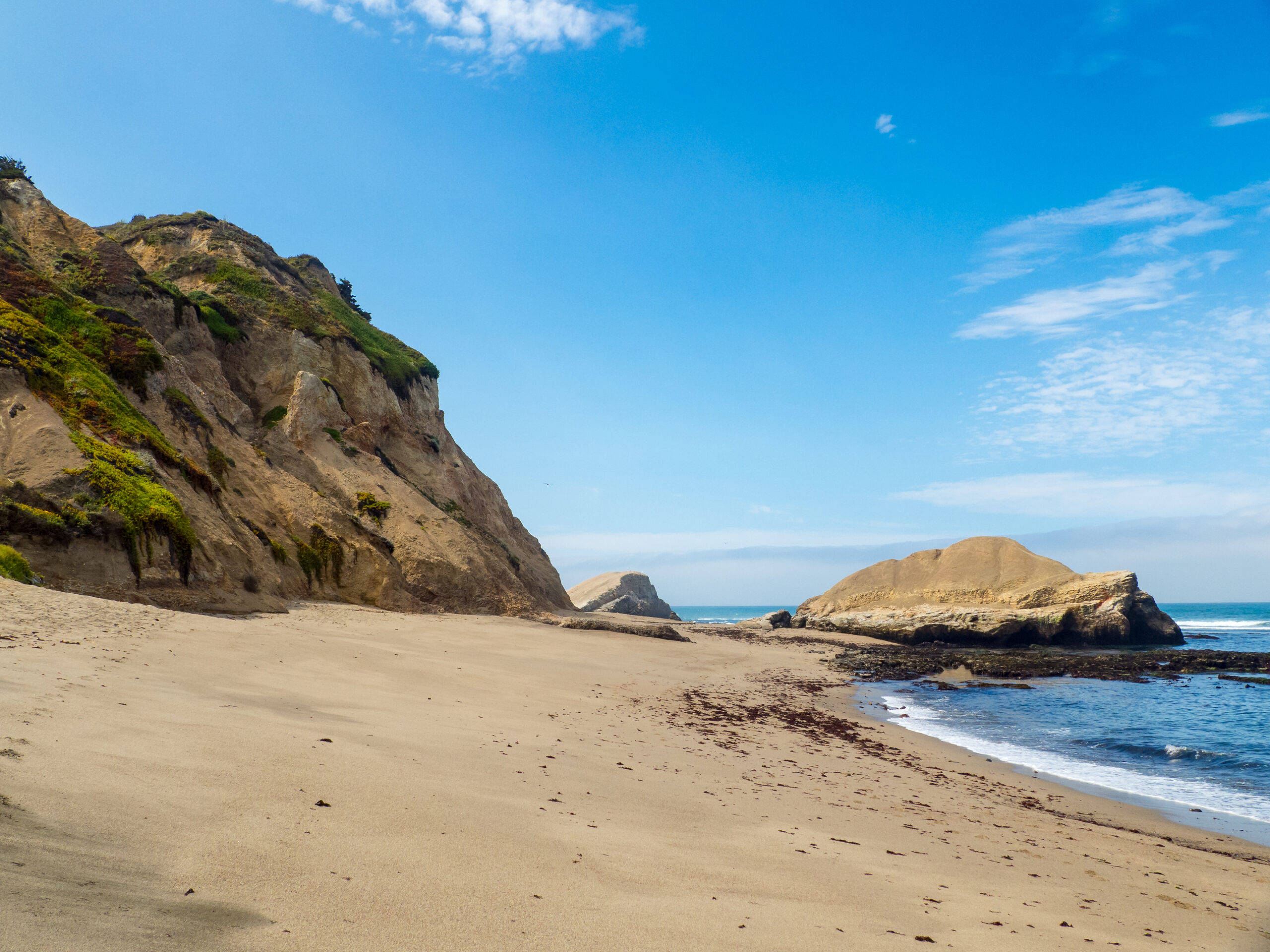 Greyhound Rock Beach near Davenport, California. View of the sandy beach with tall cliffs and the main greyhound rock.