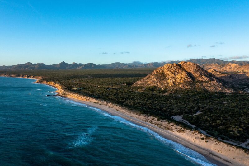 A breathtaking aerial view of Cabo Pulmo's rocky coastline and vibrant blue sea at sunrise