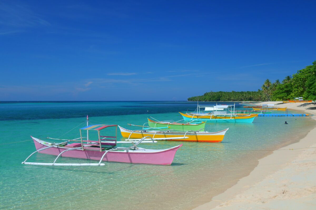 Colorful boats moored on the azure clear surface of the island of Siargao, Philippines
