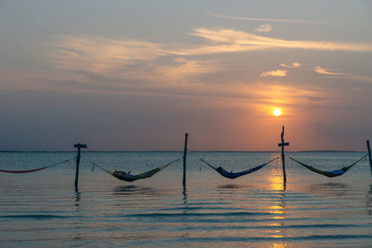 Relaxing in a hammock over the water on sunset, Isla Holbox, Mexico.