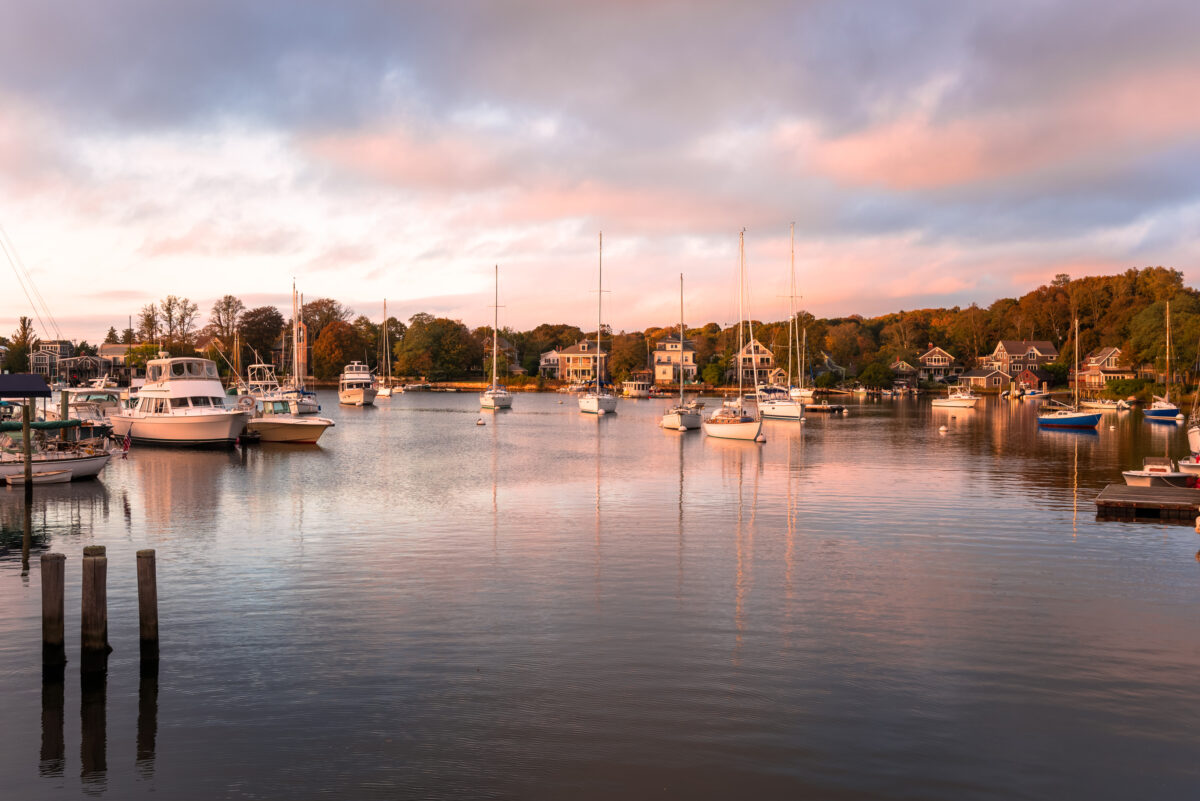 Yachts in a beautiful harbour surrounded by trees at sunset. Beautiful harbour with anchored sailboats at sunset in autumn. Falmouth, Cape Cod, MA, USA