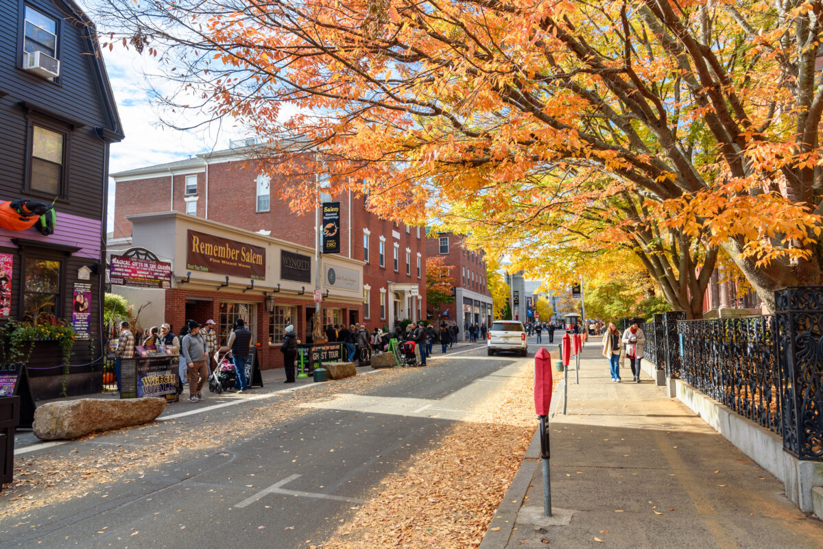 Tourists walking along Essex St. , close to traffic, on a sunny morning. Salem is famous for the witch trials of 1692, which strongly informs the city's cultural identity into the present.
