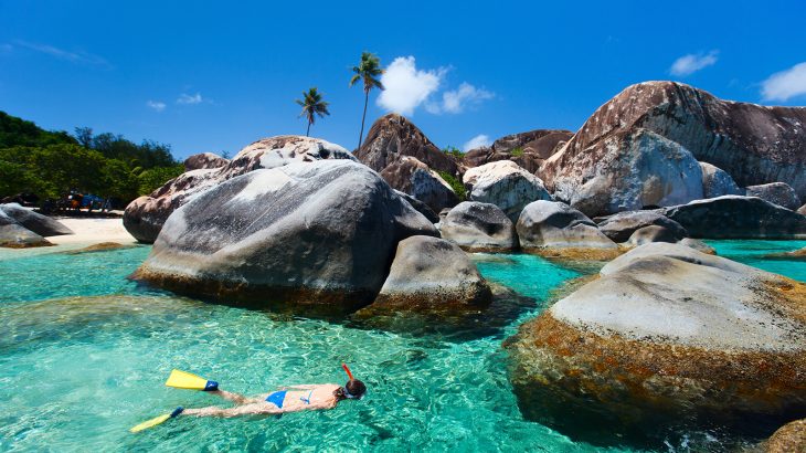 woman-snorkeling-turquoise-water-surrounded-by-rocks